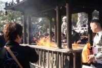 Beberapa orang membakar uang kertas sembahyang dan replika barang-barang di depan makam saat perayaan Qingming, sebuah tradisi kuno yang masih lestari hingga kini sebagai wujud penghormatan kepada leluhur. Aroma dupa dan asap pembakaran ritual ini memenuhi udara, menciptakan suasana khidmat dan reflektif di pemakaman.