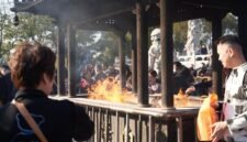 Beberapa orang membakar uang kertas sembahyang dan replika barang-barang di depan makam saat perayaan Qingming, sebuah tradisi kuno yang masih lestari hingga kini sebagai wujud penghormatan kepada leluhur. Aroma dupa dan asap pembakaran ritual ini memenuhi udara, menciptakan suasana khidmat dan reflektif di pemakaman.