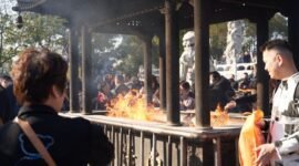 Beberapa orang membakar uang kertas sembahyang dan replika barang-barang di depan makam saat perayaan Qingming, sebuah tradisi kuno yang masih lestari hingga kini sebagai wujud penghormatan kepada leluhur. Aroma dupa dan asap pembakaran ritual ini memenuhi udara, menciptakan suasana khidmat dan reflektif di pemakaman.