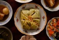 Meja makan dipenuhi aneka hidangan khas Peranakan yang memukau mata dengan warna-warni cerah dan aroma rempah menggoda, sebuah perayaan kekayaan kuliner yang melambangkan harmonisasi budaya. Setiap piring menceritakan warisan berharga dari generasi ke generasi, siap memanjakan lidah dan membawa kita pada perjalanan rasa yang tak terlupakan.