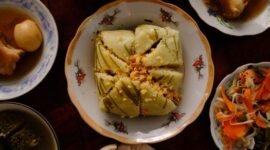Meja makan dipenuhi aneka hidangan khas Peranakan yang memukau mata dengan warna-warni cerah dan aroma rempah menggoda, sebuah perayaan kekayaan kuliner yang melambangkan harmonisasi budaya. Setiap piring menceritakan warisan berharga dari generasi ke generasi, siap memanjakan lidah dan membawa kita pada perjalanan rasa yang tak terlupakan.