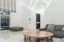 Ruang keluarga yang tertata rapi dengan banyak cahaya alami dan sentuhan tanaman hijau, mencerminkan prinsip-prinsip feng shui modern untuk menciptakan suasana yang harmonis dan menenangkan. Penataan ini bertujuan untuk memperlancar aliran energi positif di dalam rumah.