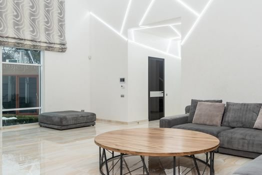 Ruang keluarga yang tertata rapi dengan banyak cahaya alami dan sentuhan tanaman hijau, mencerminkan prinsip-prinsip feng shui modern untuk menciptakan suasana yang harmonis dan menenangkan. Penataan ini bertujuan untuk memperlancar aliran energi positif di dalam rumah.