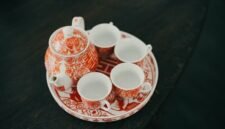 Sebuah poci tanah liat berisi teh hangat yang baru diseduh, dikelilingi cangkir-cangkir kecil, menggambarkan tradisi minum teh poci yang hangat dan akrab di Indonesia. Gambar ini mencerminkan esensi kebersamaan dan kenikmatan sederhana yang selalu hadir dalam ritual teh.