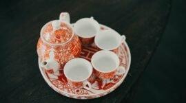 Sebuah poci tanah liat berisi teh hangat yang baru diseduh, dikelilingi cangkir-cangkir kecil, menggambarkan tradisi minum teh poci yang hangat dan akrab di Indonesia. Gambar ini mencerminkan esensi kebersamaan dan kenikmatan sederhana yang selalu hadir dalam ritual teh.