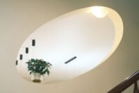 Sebuah ruangan dengan desain modern yang memadukan prinsip feng shui, terlihat dari penataan furnitur yang rapi serta kehadiran tanaman hijau yang menyegarkan, menciptakan aliran energi positif yang harmonis. Penempatan cermin strategis di sudut ruangan juga turut memperlancar sirkulasi energi chi.