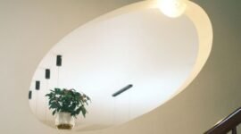 Sebuah ruangan dengan desain modern yang memadukan prinsip feng shui, terlihat dari penataan furnitur yang rapi serta kehadiran tanaman hijau yang menyegarkan, menciptakan aliran energi positif yang harmonis. Penempatan cermin strategis di sudut ruangan juga turut memperlancar sirkulasi energi chi.