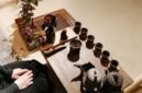 Sebuah poci teh yang sedang disajikan dengan cangkir-cangkir kecil di sekitarnya, merefleksikan kehangatan dan ritual sosial dalam tradisi minum teh yang berbeda-beda di seluruh dunia. Gambar ini menunjukkan keragaman cara menikmati teh, dari yang sederhana hingga upacara yang rumit, sebagai bagian tak terpisahkan dari kehidupan manusia.