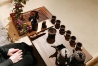 Sebuah poci teh yang sedang disajikan dengan cangkir-cangkir kecil di sekitarnya, merefleksikan kehangatan dan ritual sosial dalam tradisi minum teh yang berbeda-beda di seluruh dunia. Gambar ini menunjukkan keragaman cara menikmati teh, dari yang sederhana hingga upacara yang rumit, sebagai bagian tak terpisahkan dari kehidupan manusia.