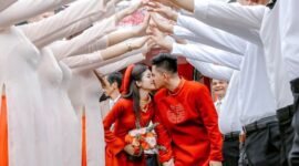Pasangan pengantin Tionghoa tengah melakukan upacara minum teh, sebuah ritual sakral yang melambangkan penghormatan kepada orang tua dan tetua keluarga, serta penerimaan restu untuk kehidupan pernikahan mereka. Gaun merah yang dikenakan mempelai wanita menjadi simbol keberuntungan dan kebahagiaan abadi dalam tradisi pernikahan Tionghoa.