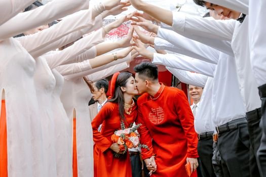 Pasangan pengantin Tionghoa tengah melakukan upacara minum teh, sebuah ritual sakral yang melambangkan penghormatan kepada orang tua dan tetua keluarga, serta penerimaan restu untuk kehidupan pernikahan mereka. Gaun merah yang dikenakan mempelai wanita menjadi simbol keberuntungan dan kebahagiaan abadi dalam tradisi pernikahan Tionghoa.
